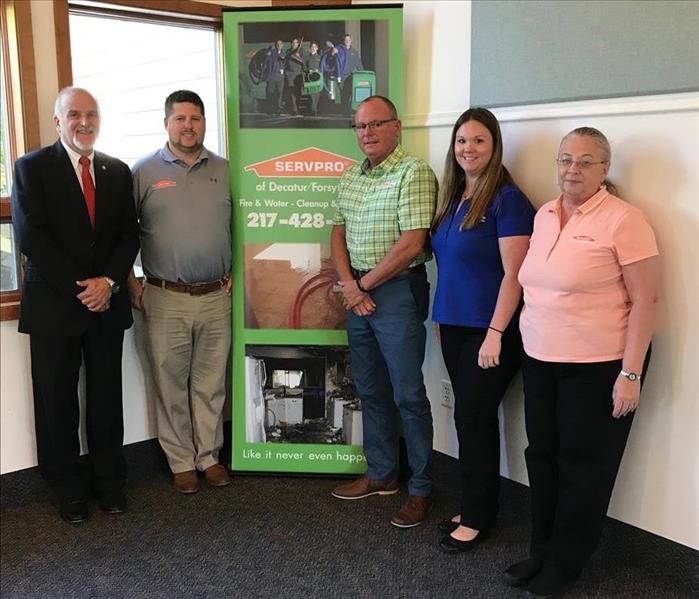 SERVPRO of Decatur/Forsyth employees standing by the SERVPRO floor banner.