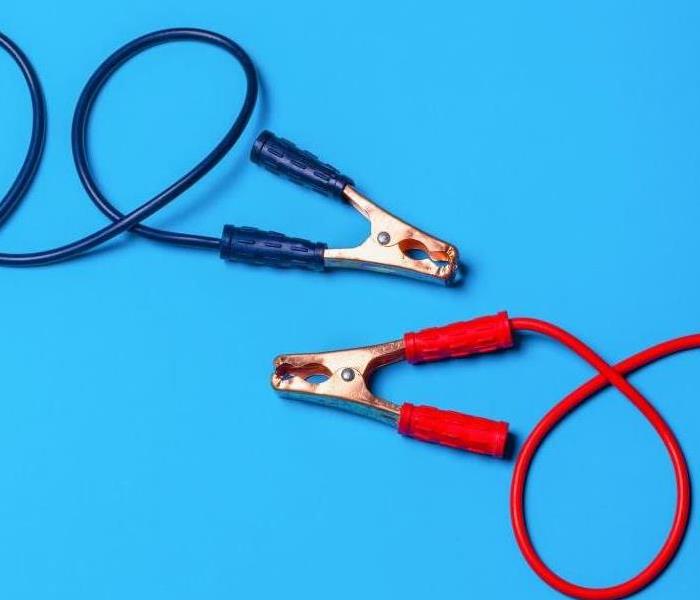 Navy blue and red jumper cables on a light blue background.