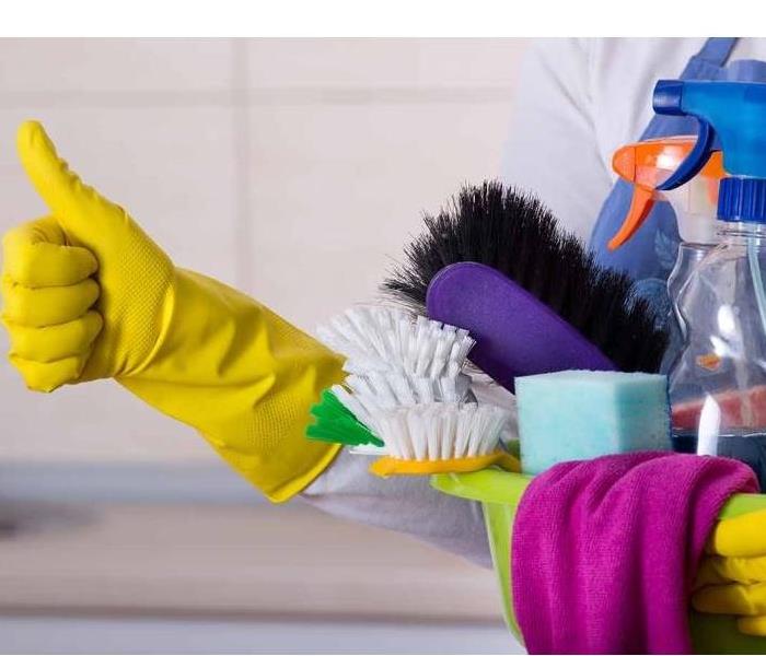 A person carrying cleaning supplies. The person is wearing yellow gloves.