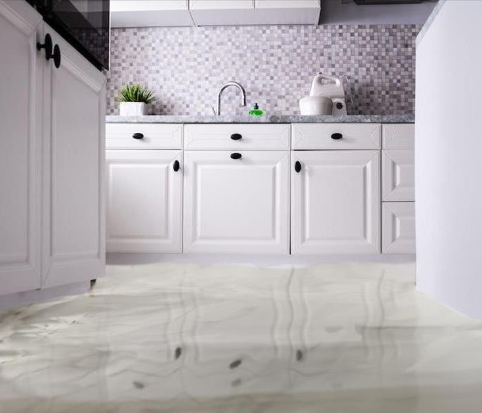 white kitchen cabinets with sanding water on the floor.