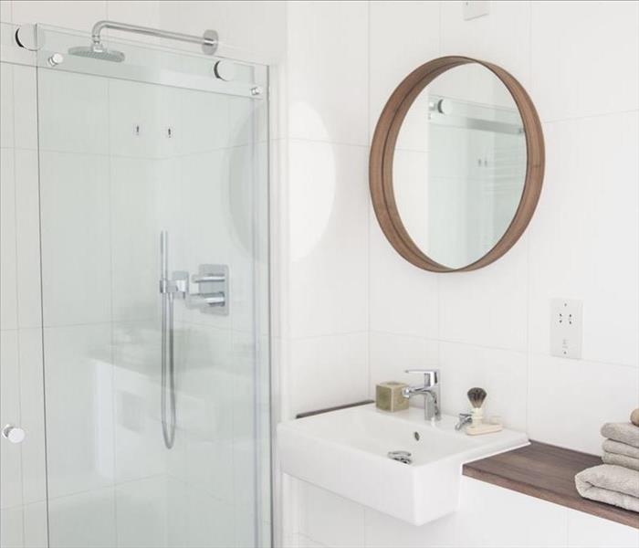 White bathroom with glass shower doors.